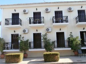 a white building with black balconies and plants at Hotel Aris in Methoni