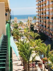 een uitzicht op een strand met palmbomen en een gebouw bij New central 2BR apartment 100m-to-beach free parking in Fuengirola