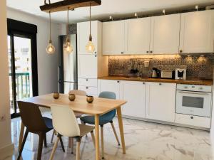 uma cozinha com armários brancos e uma mesa e cadeiras de madeira em New central 2BR apartment 100m-to-beach free parking em Fuengirola