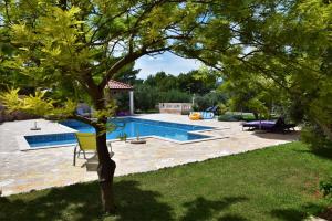 a swimming pool in a yard with a tree at Apartments Villa Barbara in Sumartin