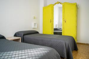 Habitación con 2 camas y armario amarillo. en Alojamientos Teatro, en Porcuna