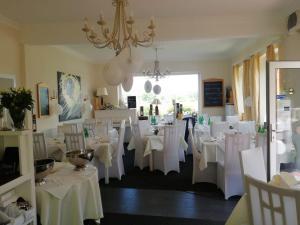 ブレッケーデにあるElbhotel Bleckedeの白いテーブルと椅子、シャンデリアのあるレストラン