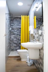 baño con lavabo y cortina de ducha amarilla en Alojamientos Teatro, en Porcuna 37 fotos más