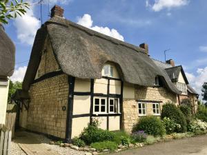 an old stone cottage with a thatched roof at Bells Cottage in Alderton