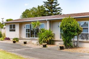 a house with trees in front of it at Waitangi Beach Units in Paihia
