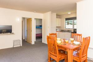 
a kitchen with a table, chairs and a refrigerator at Te Tiriti Units in Paihia
