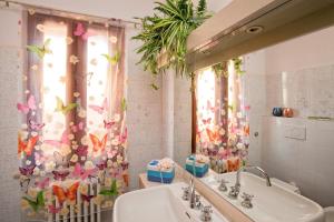 a bathroom with a sink and a shower curtain with butterflies at B&B Via della Grotta in Monsummano Terme