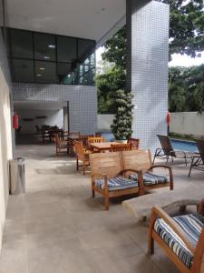 un patio con bancos y mesas de madera y una piscina en Flat Aconchegante Boa Viagem 2 Quartos, en Recife