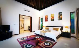 a bedroom with a large white bed and a rug at Kebun Villas & Resort in Senggigi