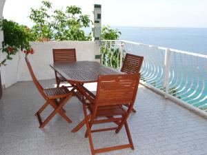 a wooden table and chairs on a balcony with the ocean at Apartments Bassi in Stara Baška