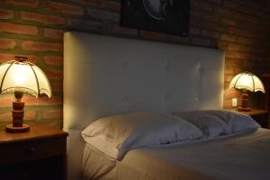 a bedroom with a white bed with two lamps at Cabañas Latitud 38.15 in Sierra de la Ventana