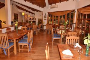 un restaurante con mesas y sillas de madera y ventanas en Casa Ceibo Hotel, en Bahía de Caráquez