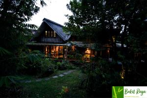 a house in the woods with lights on at Bukit Raya Guesthouse in Palangkaraya