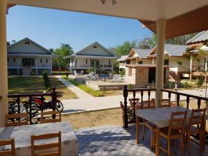a patio with tables and chairs and houses at Poolside Bungalows in Khao Lak