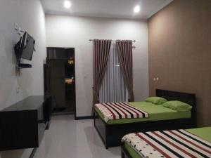 a bedroom with two beds and a television in it at Sederhana Homestay in Batukaras