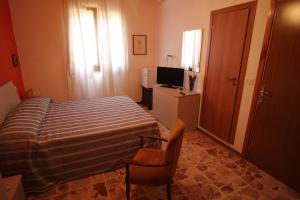 a bedroom with a bed and a chair and a television at Affittacamere Da Giorgia in Sampieri