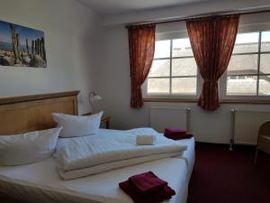 ein Hotelzimmer mit einem Bett und zwei Fenstern in der Unterkunft Hotel Alt Wittower Krug in Wiek auf Rügen 