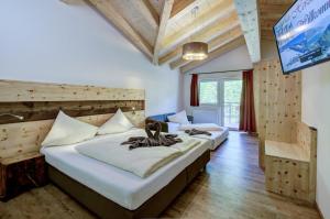 two beds in a room with a flat screen tv at Berghotel Jaga-Alm in Zell am See