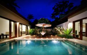 a swimming pool at night with an umbrella at Kebun Villas & Resort in Senggigi