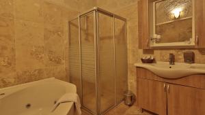 a bathroom with a shower and a tub and a sink at Vezir Cave Suites in Göreme