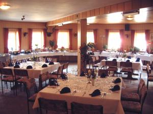 a banquet hall with tables with white tablecloths at Hotel Auerhahn in Grevenkrug