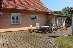 a wooden deck with a table and chairs on a house at Landhaus Peene in Sophienhof