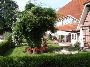 a tree in a yard with a fountain and flowers at Hotel Auerhahn in Grevenkrug