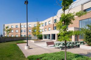 eine Gruppe Picknicktische vor einem Gebäude in der Unterkunft Residence & Conference Centre - King City in King City