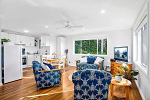 cocina y sala de estar con sillas azules y mesa en Jetty Beach Splendour Apartment en Coffs Harbour