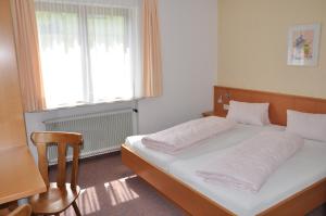 a bedroom with a bed and a window and a chair at Haus Berchtold in Alberschwende