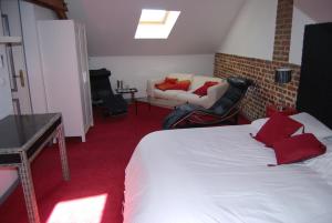 a bedroom with a bed with red pillows and a couch at Clos de Royaucourt in Royaucourt
