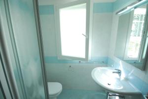 bagno con lavandino, servizi igienici e specchio di Villa Palme a Lignano Sabbiadoro
