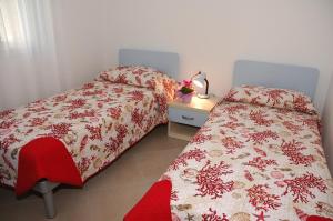 una camera con due letti e un tavolo con una lampada di Villa Palme a Lignano Sabbiadoro