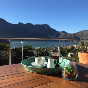 Hout Bay Breeze في هوت باي: صينية مع أكواب وقهوة على طاولة على سطح السفينة