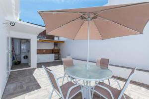 a glass table with chairs and an umbrella on a patio at Casa Alma in Marbella