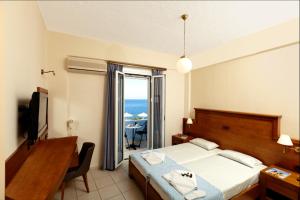 a bedroom with a bed and a desk and a television at Giorgi's Blue Apartments in Kalathas