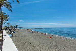 a beach with people laying on the sand and the ocean at Casa Alma in Marbella