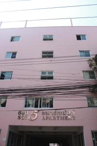 a pink building with a sign in front of it at Soi 5 Apartment in Pattaya