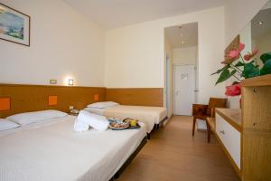 ミラノ・マリッティマにあるHotel Ridolfiのベッド2台と食料品のトレイが備わるホテルルームです。