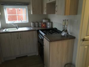 a small kitchen with a stove and a sink at Craigrossie lodge33 in Auchterarder