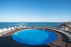 a swimming pool with chairs and the ocean in the background at Hotel El Puerto by Pierre Vacances in Fuengirola