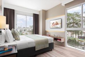 a hotel room with a bed and large windows at Citadines Regency Saigon in Ho Chi Minh City