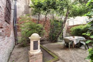 um pequeno pátio com uma mesa e uma parede de tijolos em Cà Malvasia House With Garden em Veneza