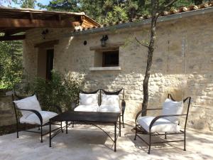 um pátio com 4 cadeiras e uma mesa com almofadas em B&B Le Deffends de Redon em Montbrun-les-Bains