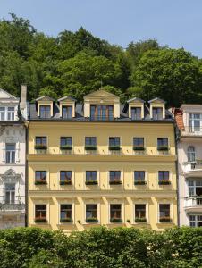 ein gelbes Gebäude mit Balkon an der Seite in der Unterkunft Boutique Hotel Corso in Karlsbad