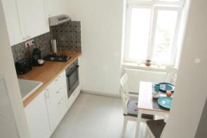 una pequeña cocina con mesa y ventana en Enjoy Apartman, en Sopron