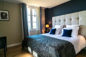a bedroom with a large bed with blue and white pillows at New Cottage & spa de nage Guesthouse in Honfleur