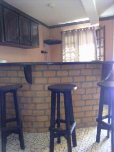 a kitchen with two bar stools and a brick wall at Villa Cassis in Ivato