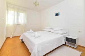a white bedroom with a bed with white sheets and pillows at Apartments Evelin in Makarska