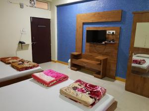 a room with three beds and a tv in it at Hotel Shri Radhe Krishna in Godarpura